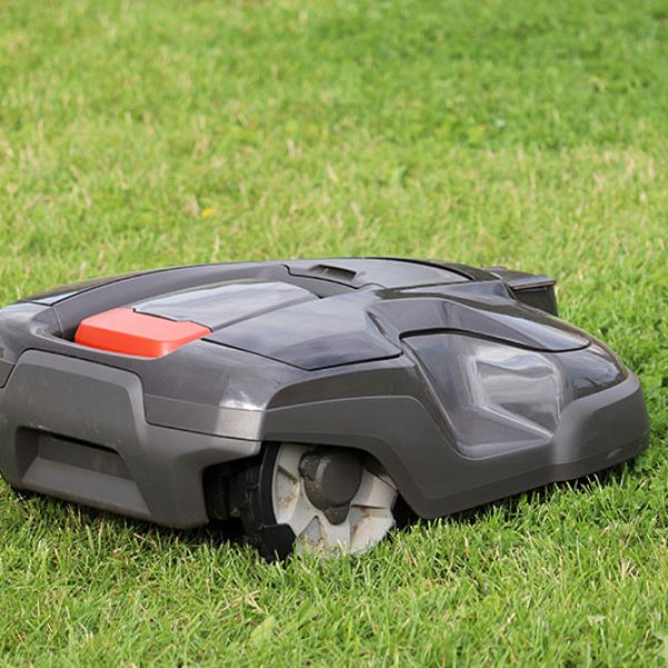 Robotic lawn mower mowing grass on a meadow. Automower in summer