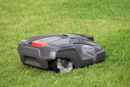 Robotic lawn mower mowing grass on a meadow. Automower in summer